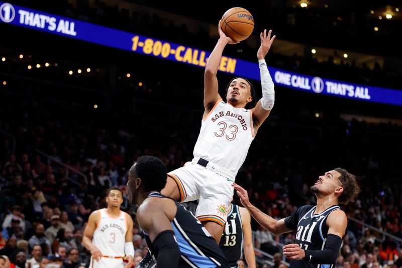 ATLANTA, GEORGIA - JANUARY 15: Tre Jones #33 of the San Antonio Spurs shoots over Trae Young #11 of the Atlanta Hawks during the second half at State Farm Arena on January 15, 2024 in Atlanta, Georgia. NOTE TO USER: User expressly acknowledges and agrees that, by downloading and or using this photograph, User is consenting to the terms and conditions of the Getty Images License Agreement. (Photo by Alex Slitz/Getty Images)