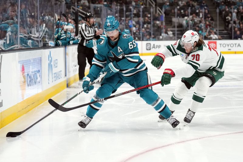 Mar 11, 2023; San Jose, California, USA; San Jose Sharks defenseman Erik Karlsson (65) skates with the puck against Minnesota Wild center Oskar Sundqvist (70) during the second period at SAP Center at San Jose. Mandatory Credit: Darren Yamashita-USA TODAY Sports