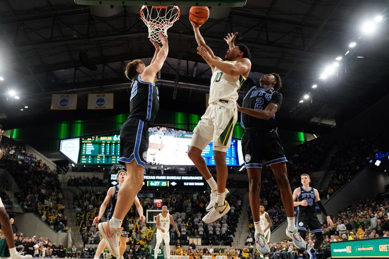 Jan 9, 2024; Waco, Texas, USA;  Baylor Bears guard RayJ Dennis (10) scores a layup between Brigham Young Cougars guard Spencer Johnson (20) and guard Jaxson Robinson (2) during the second half at Paul and Alejandra Foster Pavilion. Mandatory Credit: Chris Jones-USA TODAY Sports