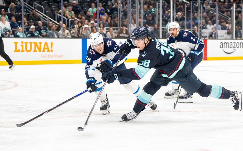 Mar 16, 2025; Seattle, Washington, USA;  Seattle Kraken foward Jani Nyman (38) takes a shot against Winnipeg Jets defenseman Haydn Fleury (24) and defenseman Dylan DeMelo (2) during the third period at Climate Pledge Arena. Mandatory Credit: Stephen Brashear-Imagn Images