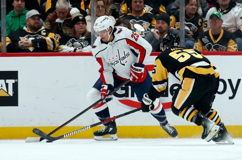 Jan 2, 2024; Pittsburgh, Pennsylvania, USA;  Washington Capitals defenseman Ethan Bear (25) moves the puck against Pittsburgh Penguins center Noel Acciari (55) during the second period at PPG Paints Arena. Mandatory Credit: Charles LeClaire-USA TODAY Sports