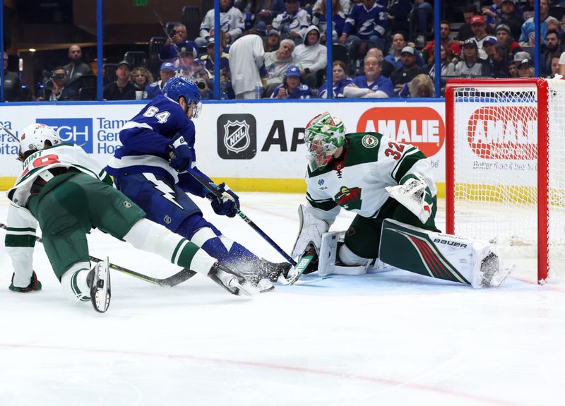 Jan 18, 2024; Tampa, Florida, USA; Tampa Bay Lightning center Tyler Motte (64) shoots as Minnesota Wild defenseman Daemon Hunt (48) and goaltender Filip Gustavsson (32) defend during the third period at Amalie Arena. Mandatory Credit: Kim Klement Neitzel-USA TODAY Sports