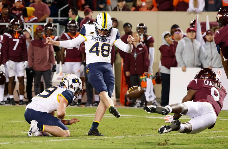 Sep 22, 2022; Blacksburg, Virginia, USA; West Virginia Mountaineers place kicker Casey Legg (48) kicks a field goal from the hold of place kicker Danny King (39) as Virginia Tech Hokies defensive back Armani Chatman (9) tries to block during the second half at Lane Stadium. Mandatory Credit: Reinhold Matay-USA TODAY Sports