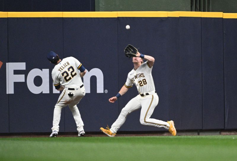 May 23, 2023; Milwaukee, Wisconsin, USA; Milwaukee Brewers right fielder Joey Wiemer (28) makes a catch in the outfield avoiding a collision with Milwaukee Brewers left fielder Christian Yelich (22) against the Houston Astros in the seventh inning  at American Family Field. Mandatory Credit: Michael McLoone-USA TODAY Sports