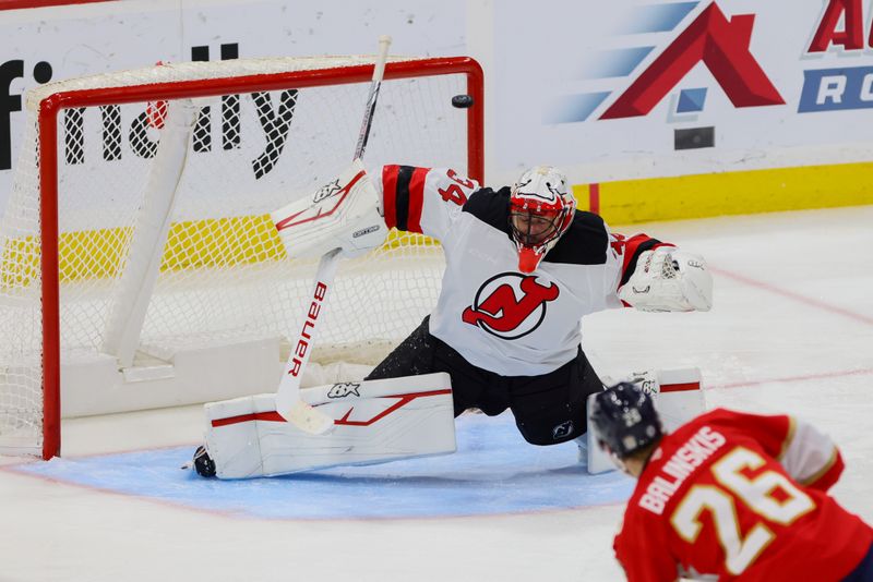 Nov 14, 2024; Sunrise, Florida, USA; New Jersey Devils goaltender Jake Allen (34) defends his net against a shot from Florida Panthers defenseman Uvis Balinskis (26) during the third period at Amerant Bank Arena. Mandatory Credit: Sam Navarro-Imagn Images