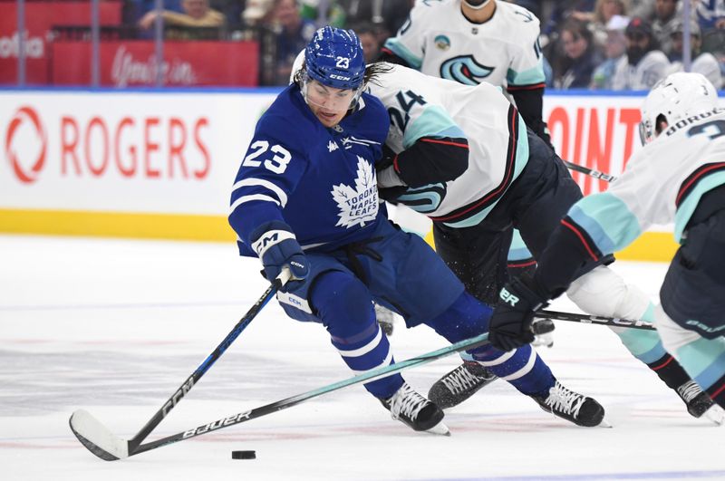 Oct 31, 2024; Toronto, Ontario, CAN;  Toronto Maple Leafs forward Matthew Knies (23) tries to carry the puck past Seattle Kraken defenseman Jamie Oleksiak (24) in the first period at Scotiabank Arena. Mandatory Credit: Dan Hamilton-Imagn Images