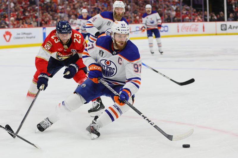 Jun 24, 2024; Sunrise, Florida, USA; Edmonton Oilers forward Connor McDavid (97) controls the puck as Florida Panthers forward Carter Verhaeghe (23) reaches to defend during the first period in game seven of the 2024 Stanley Cup Final at Amerant Bank Arena. Mandatory Credit: Sam Navarro-USA TODAY Sports