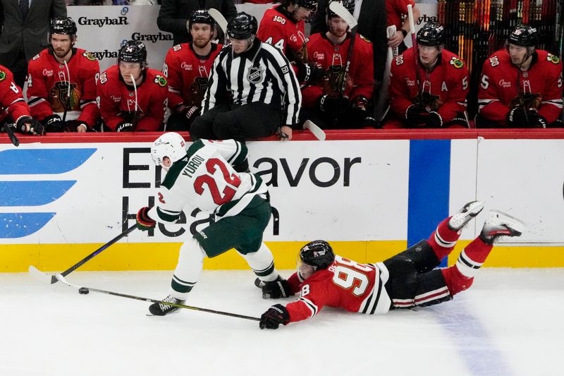 Nov 26, 2025; Chicago, Illinois, USA; Chicago Blackhawks center Connor Bedard (98) dives for the puck as Minnesota Wild right wing Danila Yurov (22) controls it during the third period at United Center. Mandatory Credit: David Banks-Imagn Images