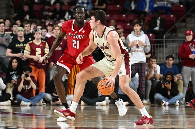 Feb 11, 2023; Chestnut Hill, Massachusetts, USA; Boston College Eagles forward Quinten Post (12) dribbles the ball in front of North Carolina State Wolfpack forward Ebenezer Dowuona (21) during the first half at the Conte Forum. Mandatory Credit: Brian Fluharty-USA TODAY Sports