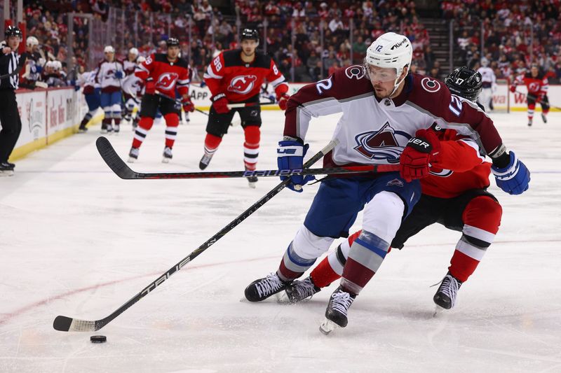 Feb 6, 2024; Newark, New Jersey, USA; Colorado Avalanche center Ryan Johansen (12) skates with the puck while being defended by New Jersey Devils defenseman Simon Nemec (17) during the third period at Prudential Center. Mandatory Credit: Ed Mulholland-USA TODAY Sports