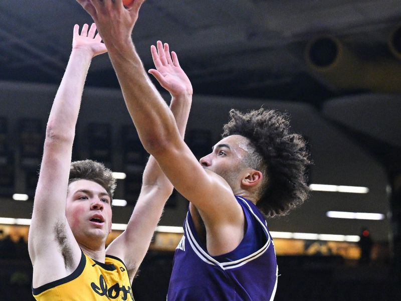 Dec 3, 2024; Iowa City, Iowa, USA; Northwestern Wildcats guard Jalen Leach (1) goes to the basket as Iowa Hawkeyes forward Pryce Sandfort (24) defends during the first half at Carver-Hawkeye Arena. Mandatory Credit: Jeffrey Becker-Imagn Images