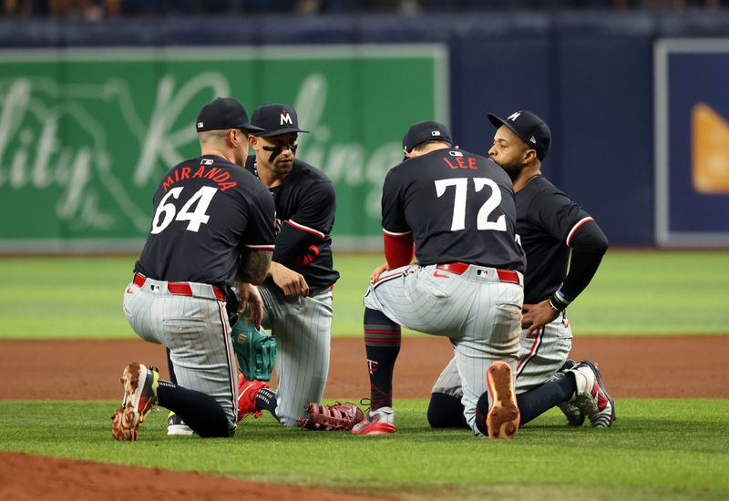 Sep 4, 2024; St. Petersburg, Florida, USA;  Minnesota Twins designated hitter Jose Miranda (64), third base Royce Lewis (23), first base Carlos Santana (30) and infielder Brooks Lee (72) kneel during a pitching change against the Tampa Bay Rays during the fourth inning at Tropicana Field. Mandatory Credit: Kim Klement Neitzel-Imagn Images