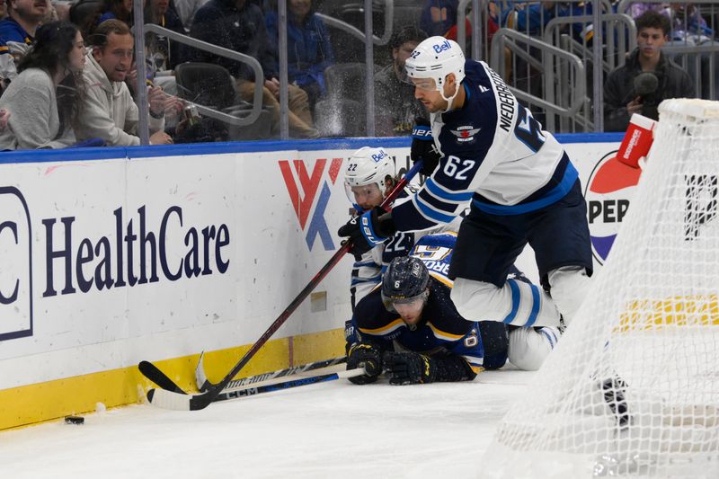 Oct 22, 2024; St. Louis, Missouri, USA; Winnipeg Jets center Mason Appleton (22) finishes his check on St. Louis Blues defenseman Philip Broberg (6) as right wing Nino Niederreiter (62) chases the puck during the third period at Enterprise Center. Mandatory Credit: Jeff Le-Imagn Images 