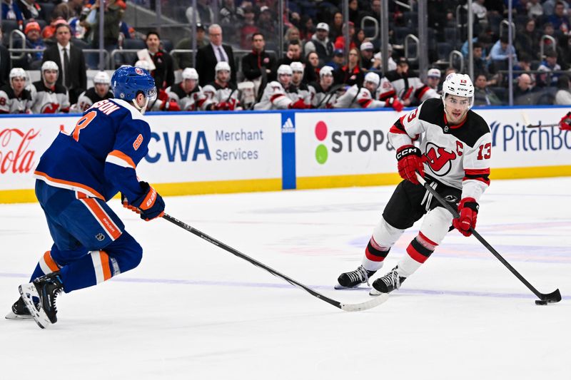 Mar 24, 2024; Elmont, New York, USA;  New Jersey Devils center Nico Hischier (13) skates the puck across the blue line defended by New York Islanders defenseman Noah Dobson (8) during the first period at UBS Arena. Mandatory Credit: Dennis Schneidler-USA TODAY Sports