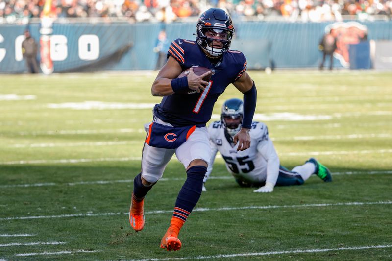 Chicago Bears quarterback Justin Fields (1) rushes with the ball past Philadelphia Eagles defensive end Brandon Graham (55) during the first half of an NFL football game, Sunday, Dec. 18, 2022, in Chicago. (AP Photo/Kamil Krzaczynski)