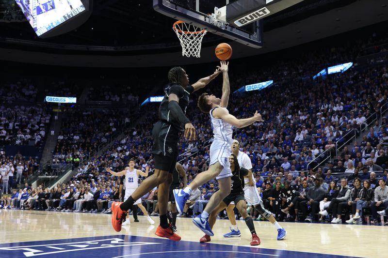 Feb 13, 2024; Provo, Utah, USA; Brigham Young Cougars guard Dallin Hall (right) lays the ball up against Central Florida Knights forward Omar Payne (left) during the second half at Marriott Center. Mandatory Credit: Rob Gray-USA TODAY Sports