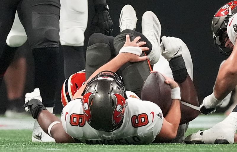 Tampa Bay Buccaneers quarterback Baker Mayfield (6) goes down after getting sacked by Atlanta Falcons defensive tackle David Onyemata (90) during the second half of an NFL football game Thursday, Oct. 3, 2024, in Atlanta. (AP Photo/John Bazemore)