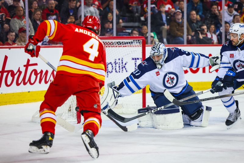 Feb 19, 2024; Calgary, Alberta, CAN; Winnipeg Jets goaltender Connor Hellebuyck (37) makes a save against Calgary Flames defenseman Rasmus Andersson (4) during the second period at Scotiabank Saddledome. Mandatory Credit: Sergei Belski-USA TODAY Sports