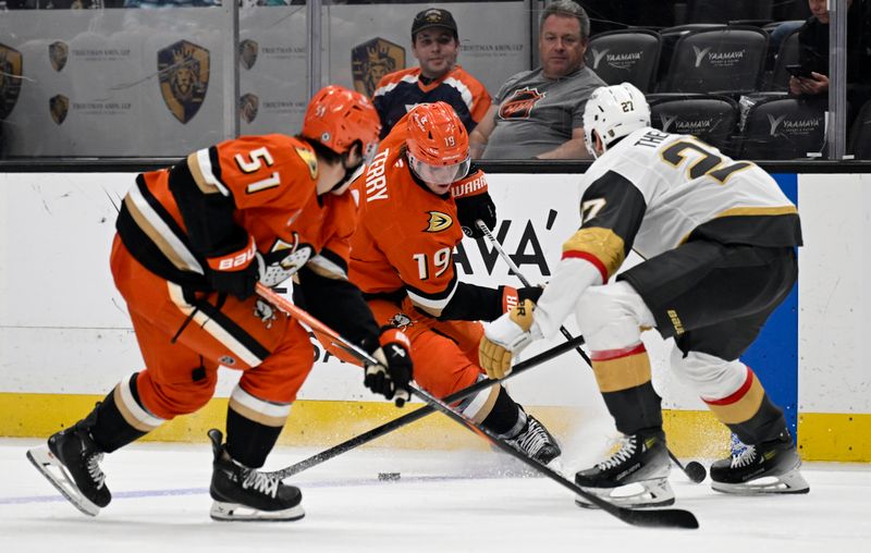 Dec 4, 2024; Anaheim, California, USA;  Anaheim Ducks right wing Troy Terry (19) looks for the puck with defenseman Olen Zellweger (51) against Vegas Golden Knights defenseman Shea Theodore (27) during the second period at Honda Center. Mandatory Credit: Alex Gallardo-Imagn Images