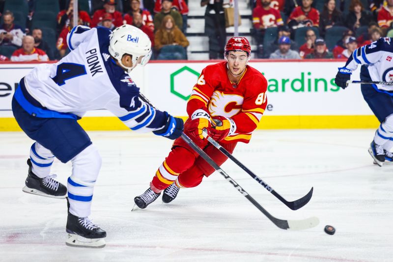 Oct 11, 2023; Calgary, Alberta, CAN; Calgary Flames left wing Andrew Mangiapane (88) and Winnipeg Jets defenseman Neal Pionk (4) battle for the puck during the second period at Scotiabank Saddledome. Mandatory Credit: Sergei Belski-USA TODAY Sports