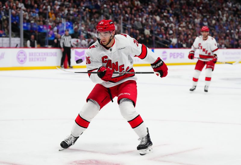 Nov 9, 2024; Denver, Colorado, USA; Carolina Hurricanes defenseman Sean Walker (26) controls a loose puck in the first period against the Colorado Avalanche at Ball Arena. Mandatory Credit: Ron Chenoy-Imagn Images