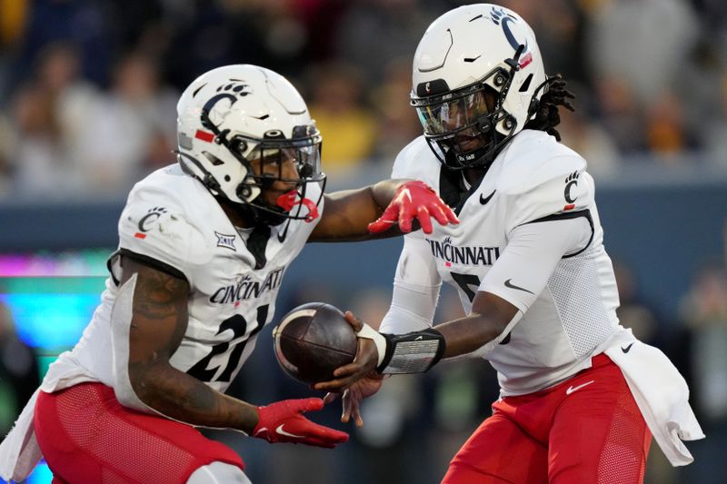 Nov 18, 2023; Morgantown, West Virginia, USA; Cincinnati Bearcats quarterback Emory Jones (5) hands the ball off to running back Corey Kiner (21) in the third quarter against the West Virginia Mountaineers at Milan Puskar Stadium. West Virginia won 42-21. Mandatory Credit: Kareem Elgazzar-USA TODAY Sports