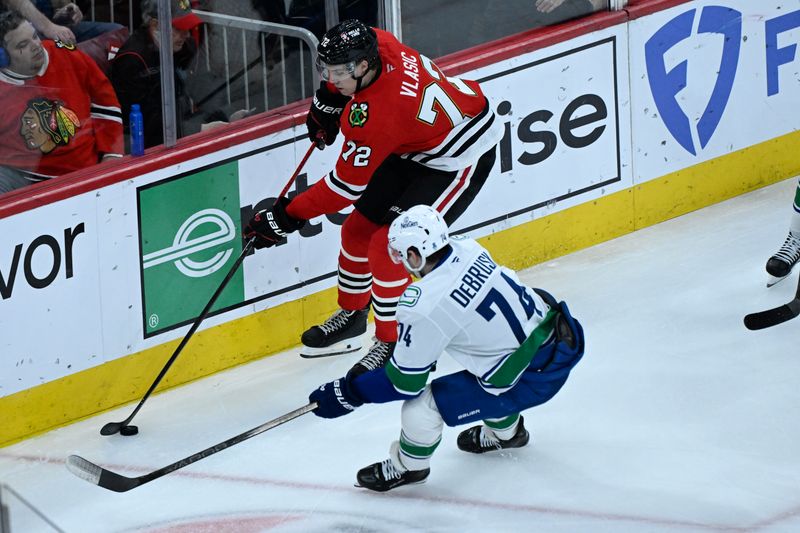 Mar 6, 2026; Chicago, Illinois, USA;  Vancouver Canucks left wing Jake DeBrusk (74) and Chicago Blackhawks defenseman Alex Vlasic (72) chase the puck during the second period at United Center. Mandatory Credit: Matt Marton-Imagn Images