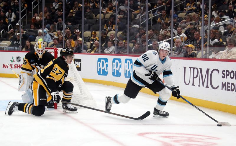 Nov 23, 2024; Pittsburgh, Pennsylvania, USA;  Utah Hockey Club center Logan Cooley (92) skates with the puck as Pittsburgh Penguins defenseman Ryan Graves (27) defends during the second period at PPG Paints Arena. Mandatory Credit: Charles LeClaire-Imagn Images