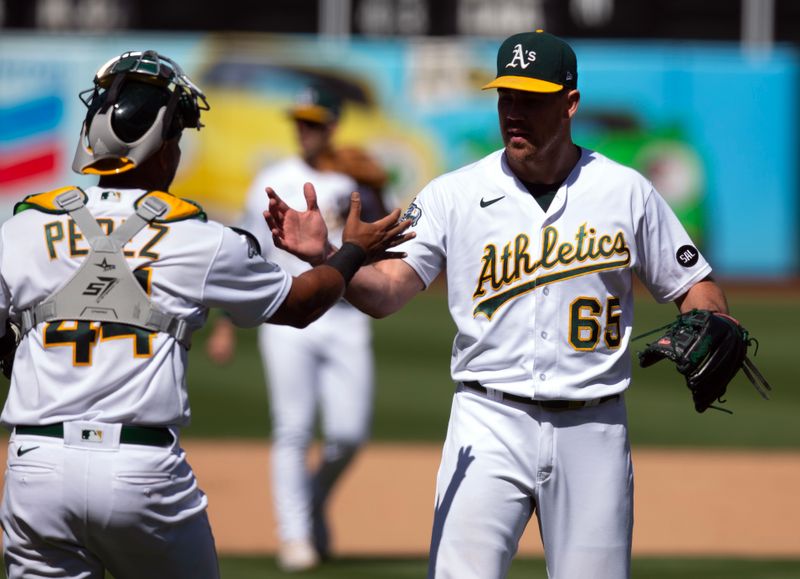 Sep 6, 2023; Oakland, California, USA; Oakland Athletics catcher Carlos Perez (44) and pitcher Trevor May (65) celebrate the 5-2 victory against the Toronto Blue Jays at Oakland-Alameda County Coliseum. Mandatory Credit: D. Ross Cameron-USA TODAY Sports