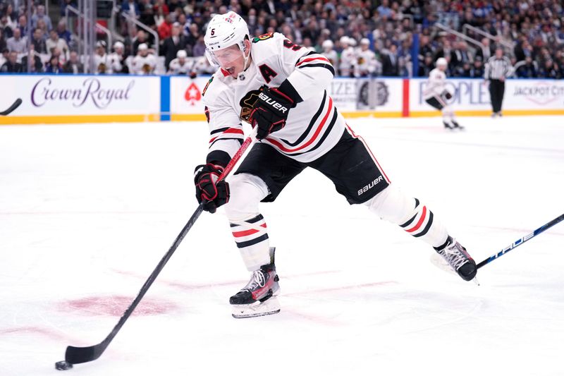 Dec 2, 2024; Toronto, Ontario, CAN; Chicago Blackhawks defenseman Connor Murphy (5) passes the puck against the Toronto Maple Leafs during the first period at Scotiabank Arena. Mandatory Credit: John E. Sokolowski-Imagn Images