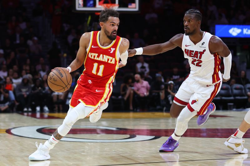 MIAMI, FLORIDA - OCTOBER 16: Trae Young #11 of the Atlanta Hawks drives against Jimmy Butler #22 of the Miami Heat during the second quarter of a preseason game at Kaseya Center on October 16, 2024 in Miami, Florida. NOTE TO USER: User expressly acknowledges and agrees that, by downloading and or using this photograph, User is consenting to the terms and conditions of the Getty Images License Agreement. (Photo by Megan Briggs/Getty Images)