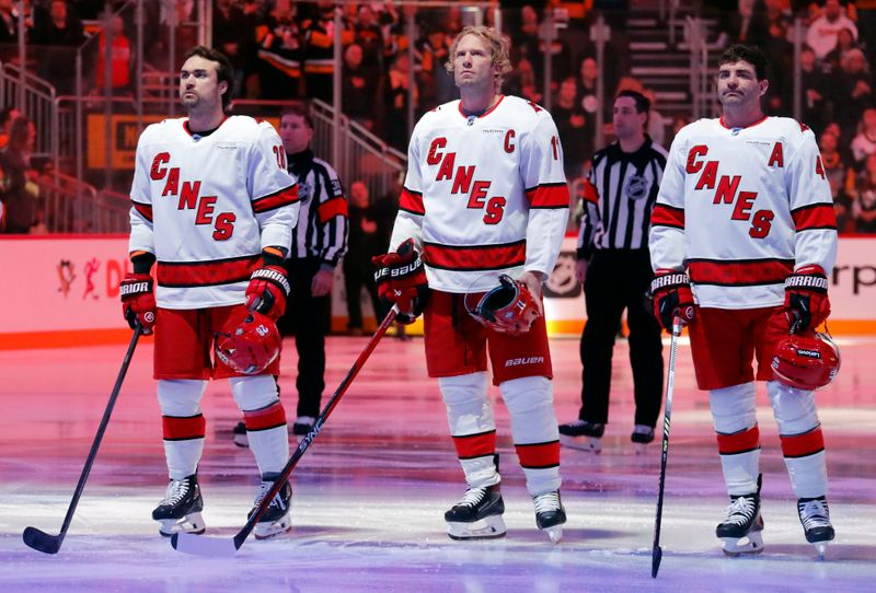 Oct 18, 2024; Pittsburgh, Pennsylvania, USA;  Carolina Hurricanes center Sebastian Aho (20) and center Jordan Staal (11) and left wing Jordan Martinook (48) stand for the national anthem against the Pittsburgh Penguins at PPG Paints Arena. Mandatory Credit: Charles LeClaire-Imagn Images