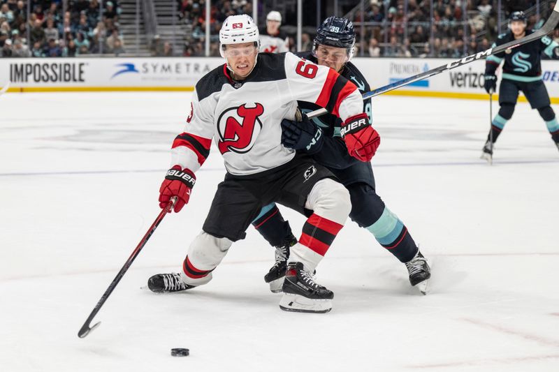 Dec 7, 2023; Seattle, Washington, USA; New Jersey Devils forward Jesper Bratt (63) battles Seattle Kraken defensman Ryker Evans (39) for the puck during the first period at Climate Pledge Arena. Mandatory Credit: Stephen Brashear-USA TODAY Sports