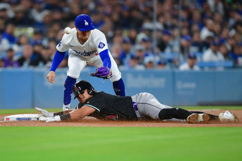 May 22, 2024; Los Angeles, California, USA; Arizona Diamondbacks catcher Gabriel Moreno (14) reaches third against Los Angeles Dodgers third baseman Enrique Hernandez (8) during the fifth inning at Dodger Stadium. Mandatory Credit: Gary A. Vasquez-USA TODAY Sports