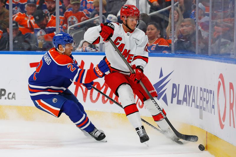 Oct 22, 2024; Edmonton, Alberta, CAN; Carolina Hurricanes forward Sebastian Aho (20) and Edmonton Oilers defensemen Evan Bouchard (2) battle along the boards for a loose puck during the second period at Rogers Place. Mandatory Credit: Perry Nelson-Imagn Images