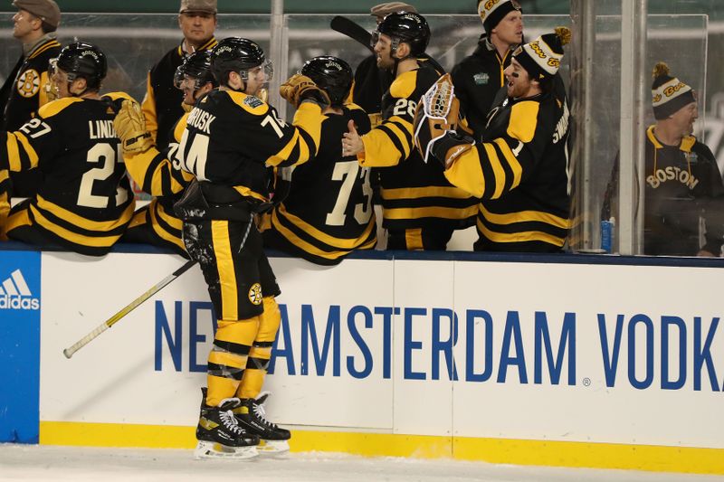 Jan 2, 2023; Boston, Massachusetts, USA; Boston Bruins left wing Jake DeBrusk (74) celebrates with his teammates after scoring a goal against the Pittsburgh Penguins during the third period of the 2023 Winter Classic ice hockey game at Fenway Park. Mandatory Credit: Paul Rutherford-USA TODAY Sports