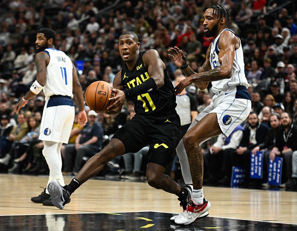 SALT LAKE CITY, UTAH - JANUARY 01: Kris Dunn #11 of the Utah Jazz drives past Derrick Jones Jr. #55 of the Dallas Mavericks during the first half of a game at Delta Center on January 01, 2024 in Salt Lake City, Utah. NOTE TO USER: User expressly acknowledges and agrees that, by downloading and or using this photograph, User is consenting to the terms and conditions of the Getty Images License Agreement. (Photo by Alex Goodlett/Getty Images)