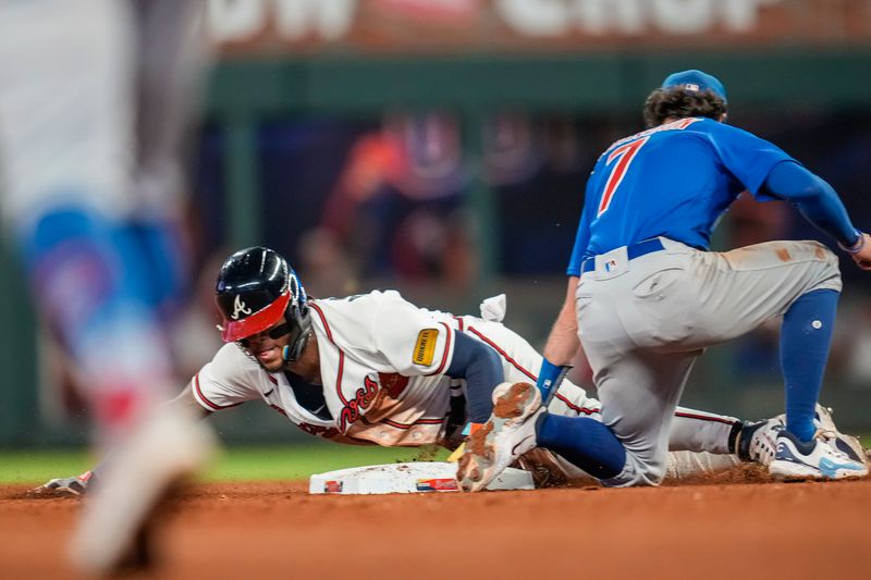 Sep 27, 2023; Cumberland, Georgia, USA; Atlanta Braves right fielder Ronald Acuna Jr. (13) steals his 70th base of the season under Chicago Cubs shortstop Dansby Swanson (7) during the tenth inning at Truist Park. Mandatory Credit: Dale Zanine-USA TODAY Sports