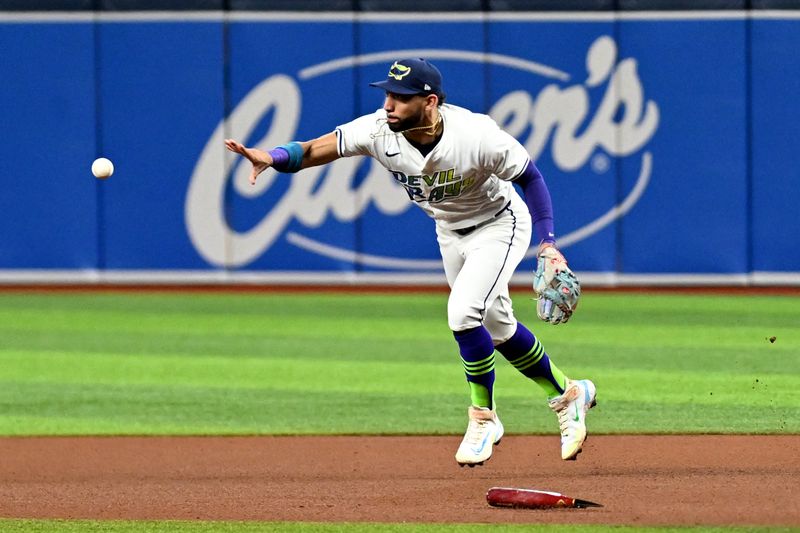 Jul 26, 2024; St. Petersburg, Florida, USA; Tampa Bay Rays second baseman Jose Caballero (7) flips the ball to second basein the fourth inning against the  Cincinnati Reds at Tropicana Field. Mandatory Credit: Jonathan Dyer-USA TODAY Sports