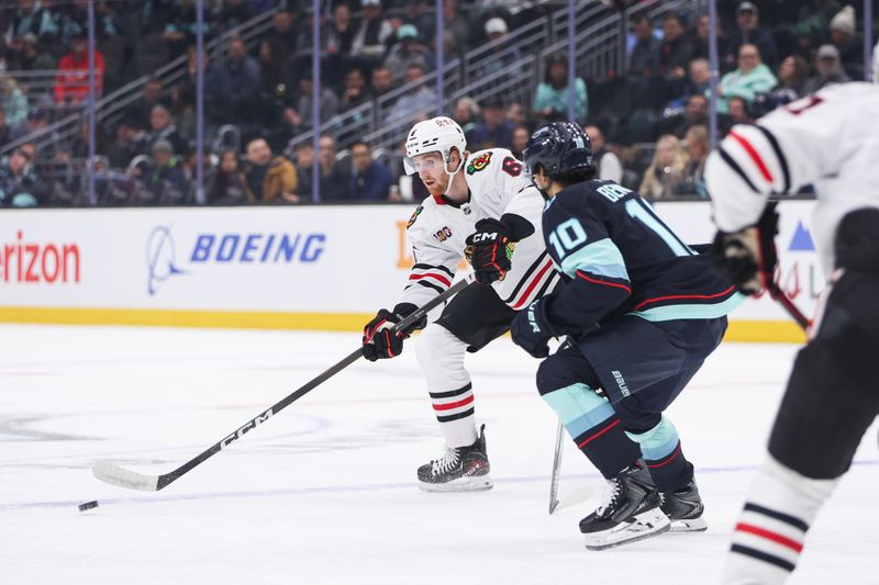 Nov 3, 2025; Seattle, Washington, USA; Chicago Blackhawks defenseman Sam Rinzel (6) passes the puck while being defended by Seattle Kraken center Matty Beniers (10) in the first period at Climate Pledge Arena. Mandatory Credit: Kevin Ng-Imagn Images