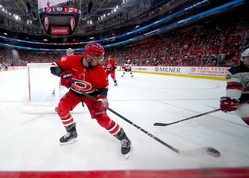 Oct 15, 2024; Raleigh, North Carolina, USA;  Carolina Hurricanes defenseman Shayne Gostisbehere (4) played the puck against the New Jersey Devils during the second period at PNC Arena. Mandatory Credit: James Guillory-Imagn Images