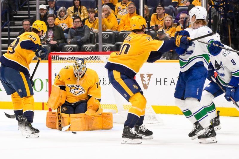 Jan 29, 2025; Nashville, Tennessee, USA;  Nashville Predators goaltender Juuse Saros (74) blocks the shot of Vancouver Canucks left wing Danton Heinen (20) during the second period at Bridgestone Arena. Mandatory Credit: Steve Roberts-Imagn Images