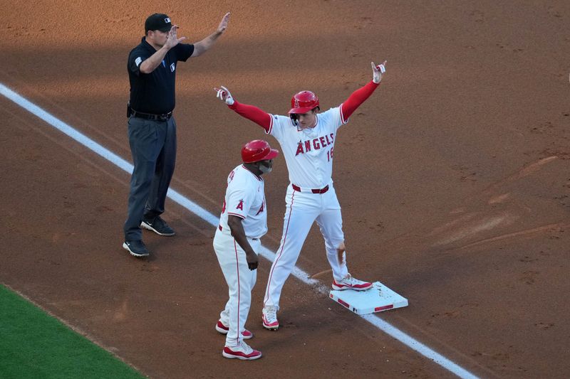 May 6, 2023; Anaheim, California, USA; Los Angeles Angels center fielder Mickey Moniak (16) celebrates after hitting a two-run triple in the first inning as third base coach Eric Young Sr. (85) watches against the Texas Rangers at Angel Stadium. Mandatory Credit: Kirby Lee-USA TODAY Sports