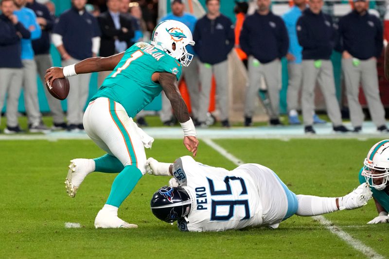 Miami Dolphins quarterback Tua Tagovailoa (1) avoids a sack by Tennessee Titans defensive tackle Kyle Peko (95) during an NFL football game, Monday, Dec. 11, 2023, in Miami Gardens, Fla. (AP Photo/Doug Benc)