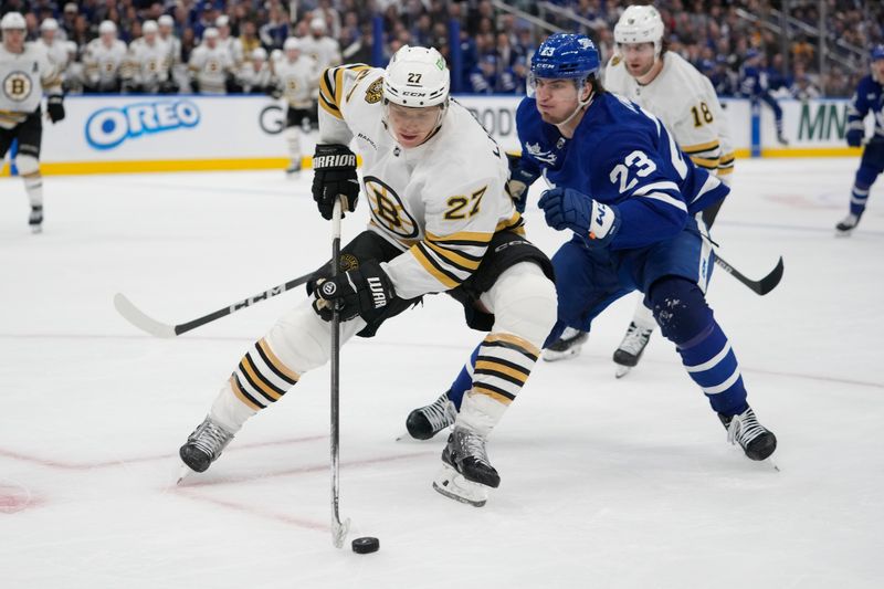 Apr 24, 2024; Toronto, Ontario, CAN; Boston Bruins defenseman Hampus Lindholm (27) controls the puck as Toronto Maple Leafs forward Matthew Knies (23) closes in during the third period of game three of the first round of the 2024 Stanley Cup Playoffs at Scotiabank Arena. Mandatory Credit: John E. Sokolowski-USA TODAY Sports