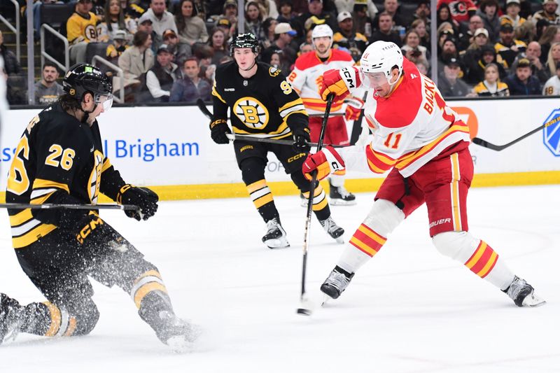 Jan 8, 2026; Boston, Massachusetts, USA; Calgary Flames center Mikael Backlund (11) shoots the puck while Boston Bruins defenseman Andrew Peeke (26) defends during the second period at TD Garden. Mandatory Credit: Bob DeChiara-Imagn Images