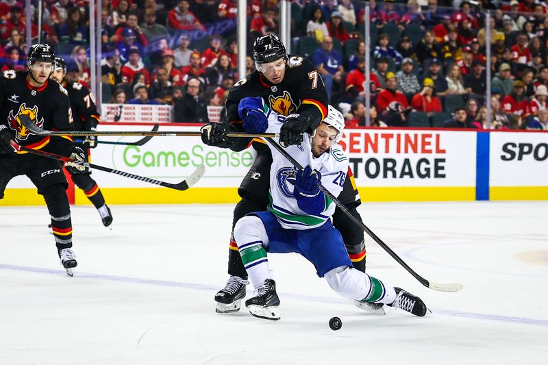 Dec 31, 2024; Calgary, Alberta, CAN; Vancouver Canucks defenseman Erik Brannstrom (26) and Calgary Flames right wing Walker Duehr (71) battles for the puck during the third period at Scotiabank Saddledome. Mandatory Credit: Sergei Belski-Imagn Images