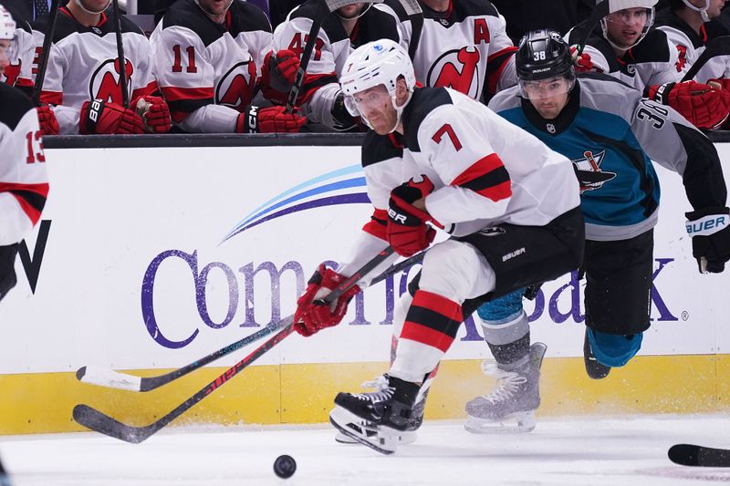 Oct 30, 2025; San Jose, California, USA;  New Jersey Devils defenseman Dougie Hamilton (7) passes the puck while defended by San Jose Sharks defenseman Mario Ferraro (38) in the first period at SAP Center at San Jose. Mandatory Credit: David Gonzales-Imagn Images