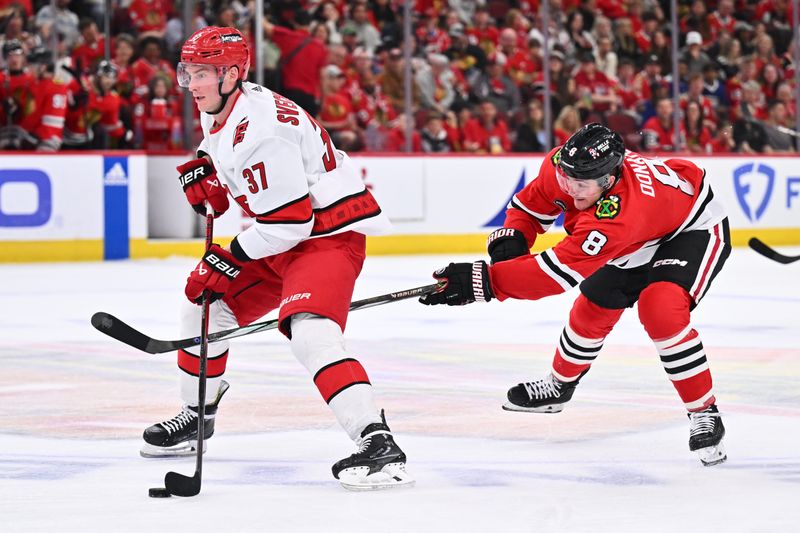 Apr 14, 2024; Chicago, Illinois, USA;  Carolina Hurricanes forward Andrei Svechnikov (37) controls the puck as Chicago Blackhawks forward Ryan Donato (8) attempts to defend from behind in the second period at United Center. Mandatory Credit: Jamie Sabau-USA TODAY Sports