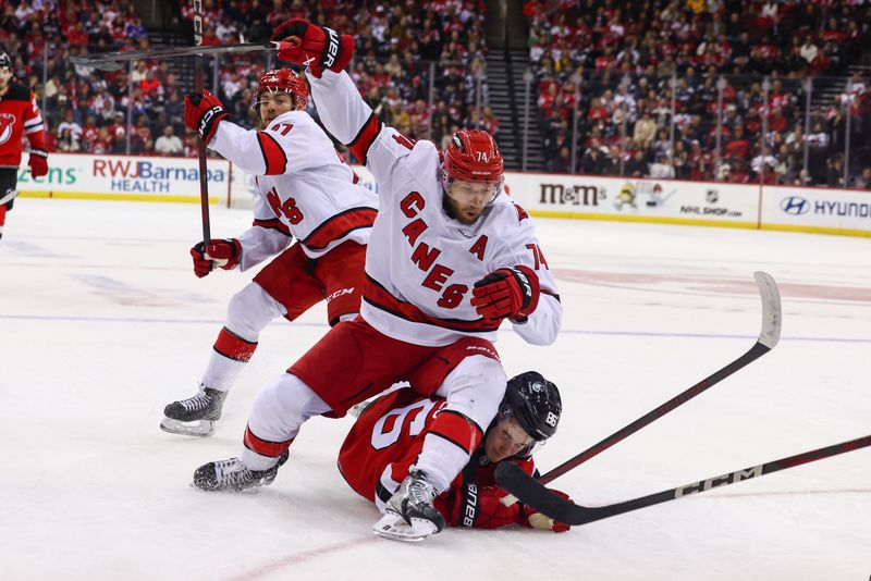 Nov 21, 2024; Newark, New Jersey, USA; Carolina Hurricanes defenseman Jaccob Slavin (74) knocks down New Jersey Devils center Jack Hughes (86) during the second period at Prudential Center. Mandatory Credit: Ed Mulholland-Imagn Images